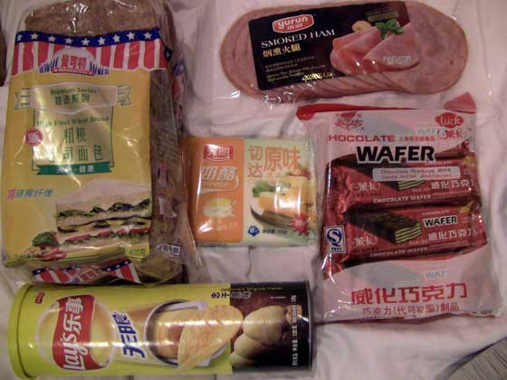 Shanghai Grocery Store Spoils When you have had all the noodles and fish head soup you can eat, it's time to get back to the essentials. We scrounged this bag of beauty from a local grocery store, god bless. Cheese is a son of a gun to find, let me tell you, and pricey at about $1.50 for six slices. The sandwich bread is mostly sweet there too and had a hard time finding the unsweetened variety. Turkey you ask? No way sailor! Pork is da meat in deez parts, and even our sliced ham has a little gristle left in for extra texture. Wooeee! Those lays are gonna taste damn good! Hey...we are backpacking!